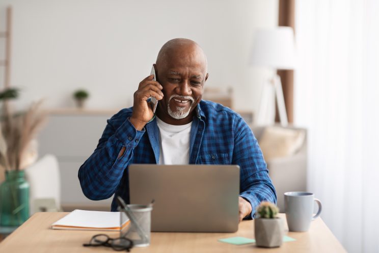 Senior male accessing support on his phone and laptop